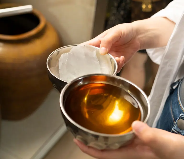 Close-up of traditional Yunnan cuisine preparation in China, featuring hands holding metal bowls.