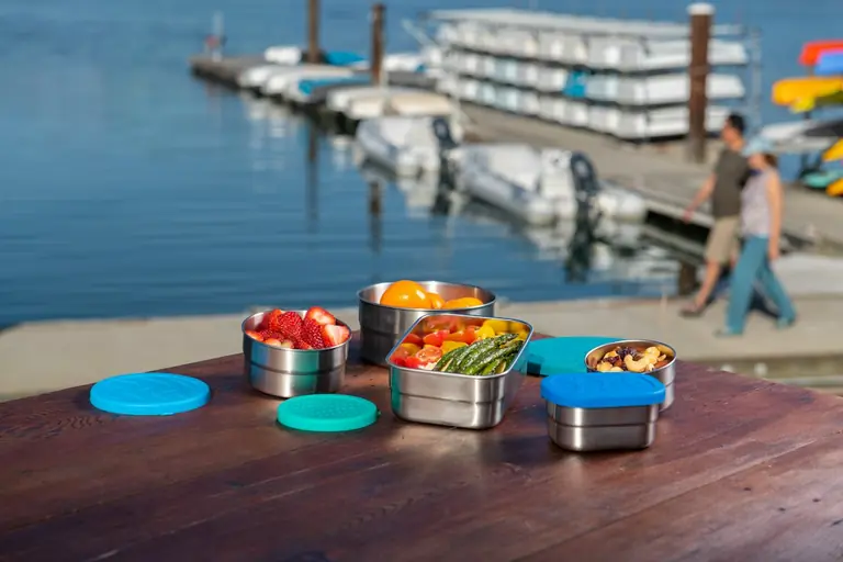 a wooden table topped with metal containers filled with fruit
