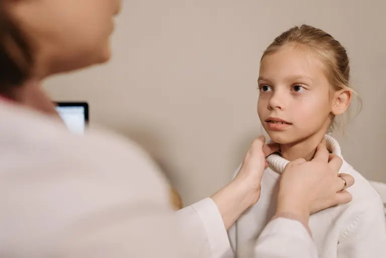 A doctor performing a medical check on a child during an appointment in a clinic.