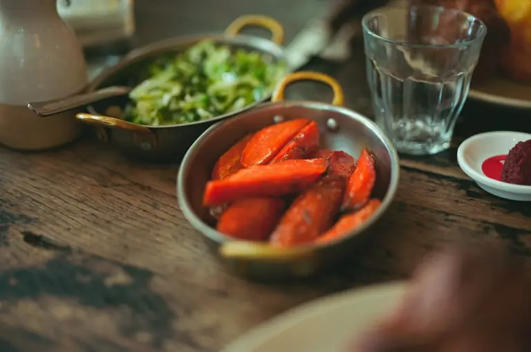 Roasted carrots and salad served in metal bowls.
