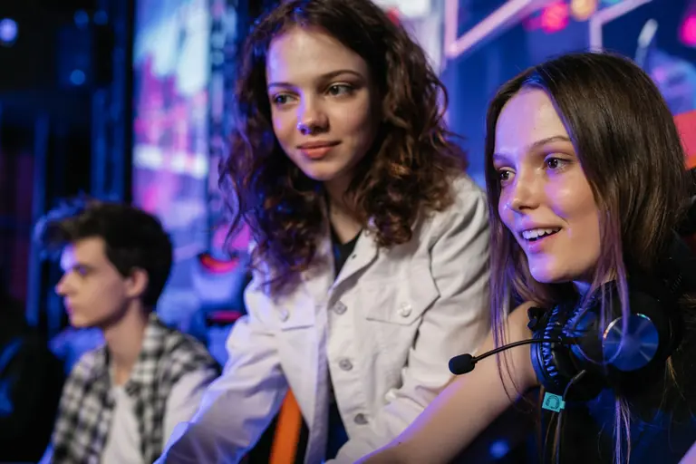 Three teenagers enjoying an immersive gaming session in a lively e-sports venue.