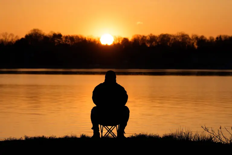 Silhouette of a person meditating by the water at sunrise in Stamford, Connecticut.